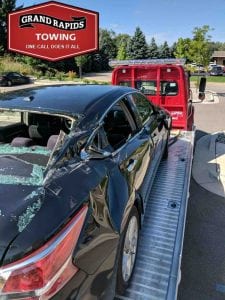 Wrecker Service on back of tow truck after Nissan crashed by Semi